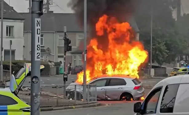 Dramatic footage shows crowds gather as car erupts into ’30ft’ flames